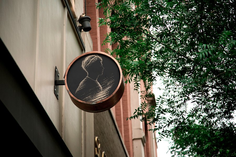 Round wall-mounted sign bearing the silhouette mark